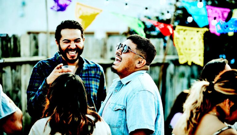A group of friends laugh together outside at a backyard party.