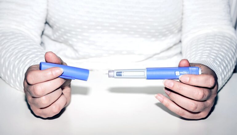 A person opens a GLP-1 medication injector.