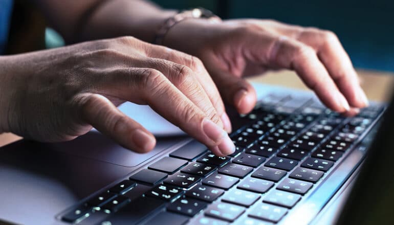 A person types on a laptop keyboard.