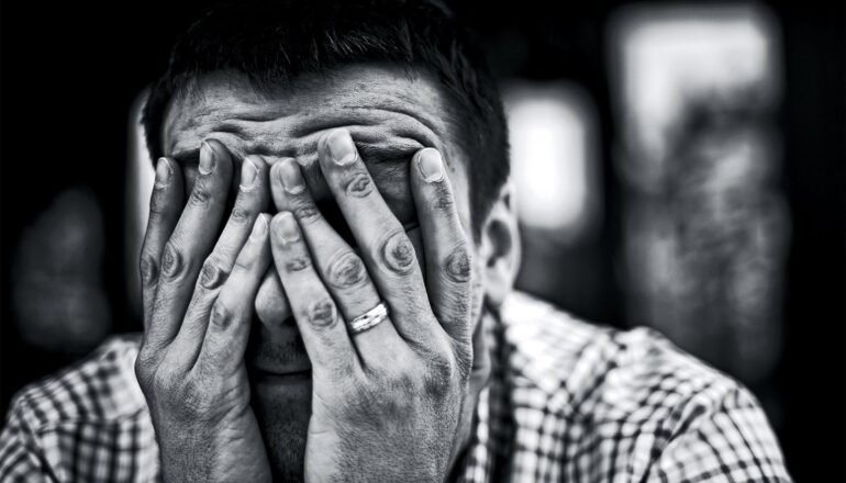 A man covers his face with both hands.