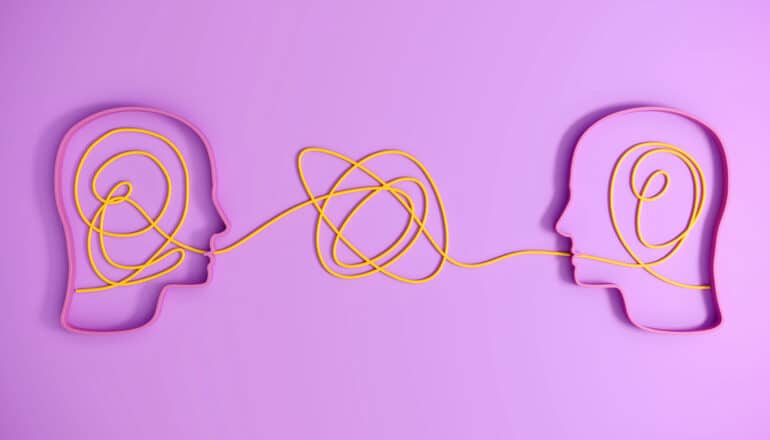 Two outlines of human heads with tangled wires in each that connect between them.