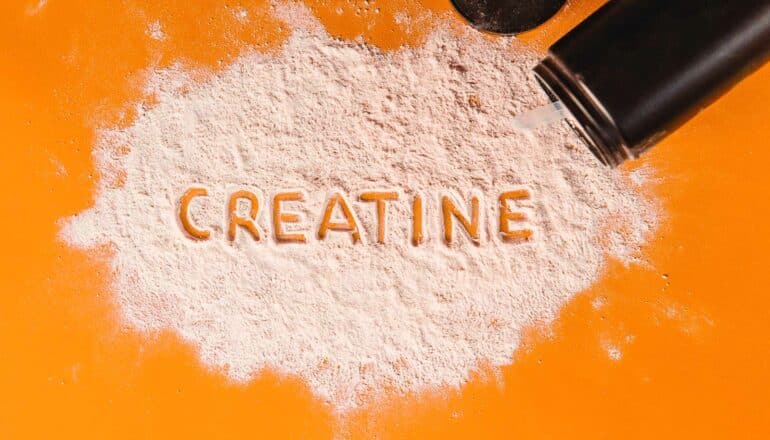 The word "creatine" is written in creatine powder on an orange background.