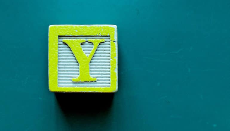 A wooden toy block with the letter Y on it.